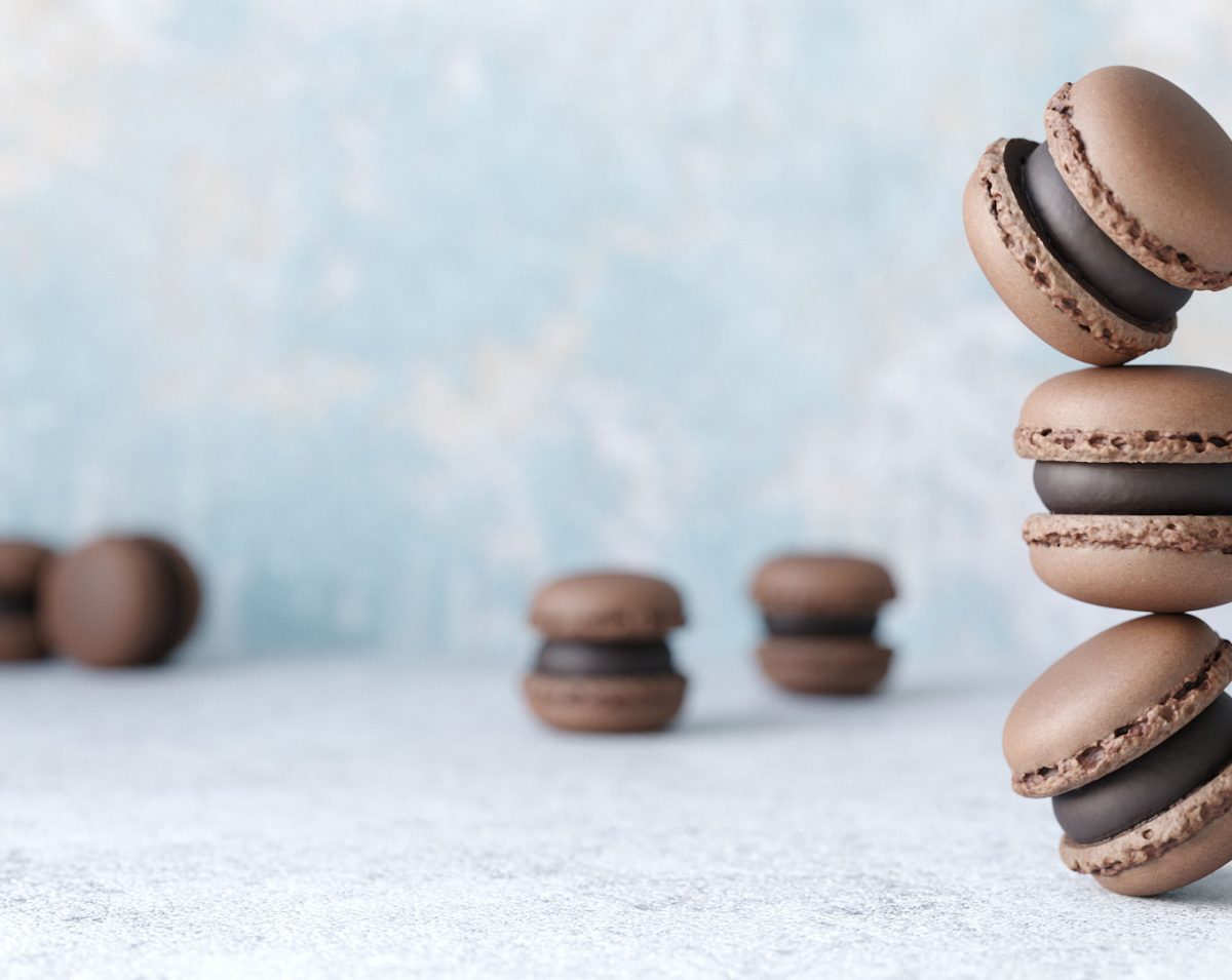 photorealistic close up rendering of a group of chocolate macaron 3d models on concrete